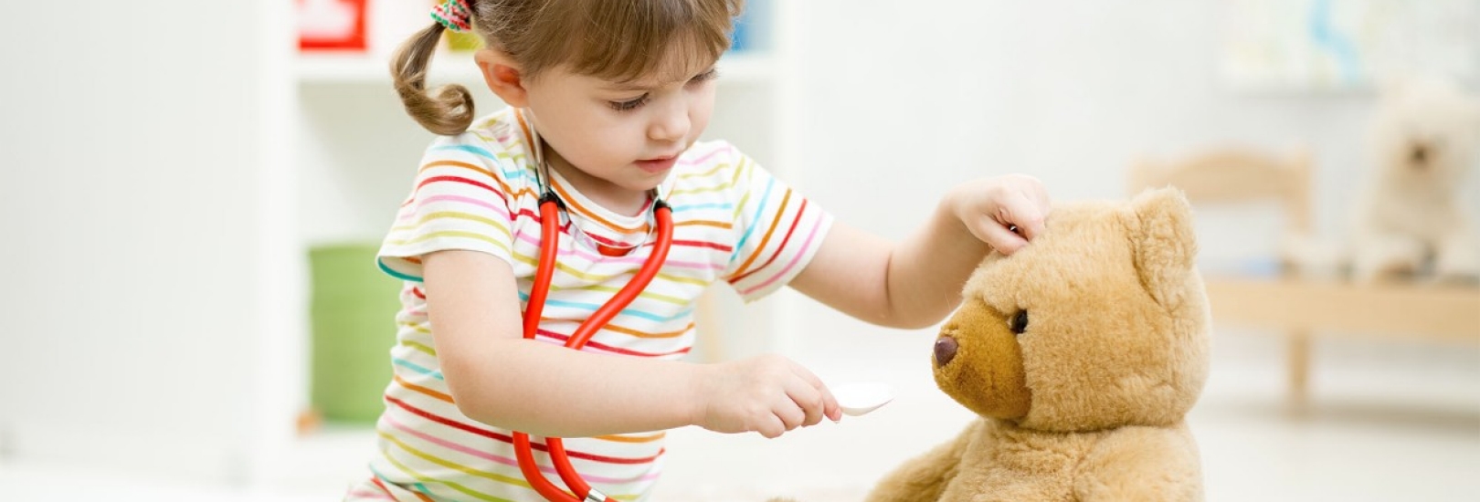 child girl playing doctor and curing plush toy